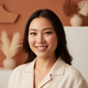Close-up portrait of a smiling East Asian woman with naturally long, curled eyelashes, conveying happiness and trust.