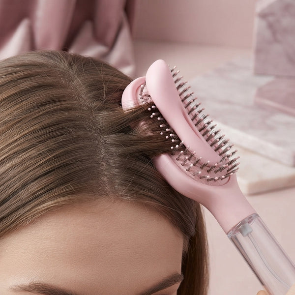 Close-up of a spray comb bristles pressing into a flexible air cushion base against a person's scalp.